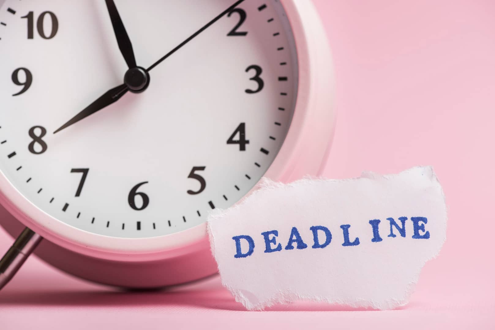 Deadline on torn paper with a clock in pink ground