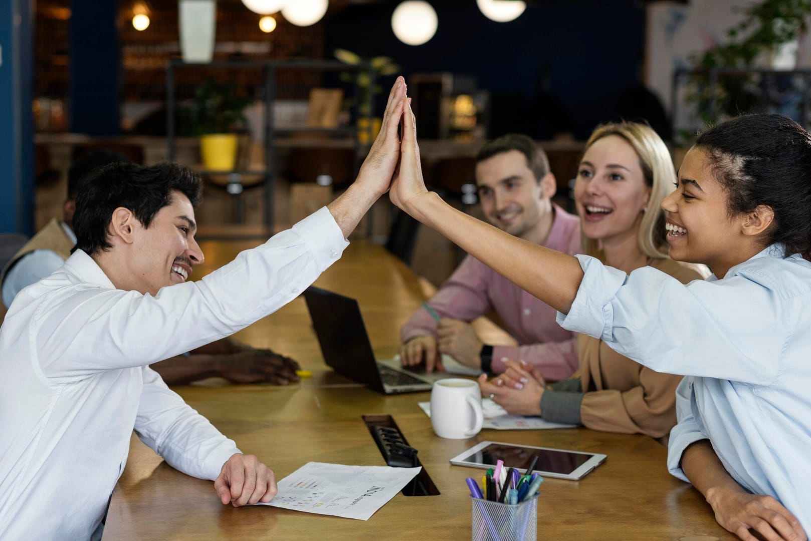 side view of people-high-fiving each other in office meeting